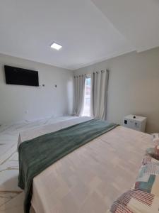 a bedroom with a large bed with a television on the wall at Hotel Avalon in Benevides