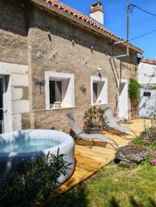 a backyard with a hot tub on a wooden deck at La fermette de Chandigon in Antran
