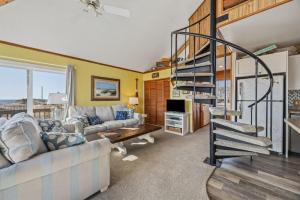 a living room with a spiral staircase in a house at 7026 - Southwind in Rodanthe