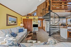 a living room with a couch and a spiral staircase at 7026 - Southwind in Rodanthe +45 photos