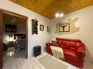 a living room with a red couch and a bedroom at Sentiero Lofts in Urubici