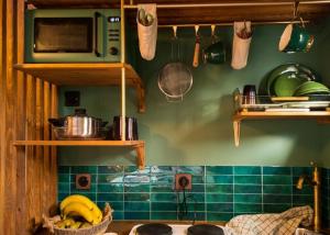 a kitchen with green walls and wooden shelves and bananas at La tiny house perdue in Saint-Blimont