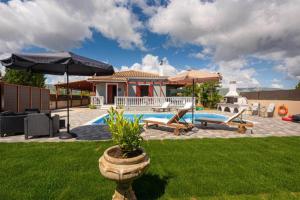 a backyard with a pool and a house with an umbrella at Pothos Villas in Zakynthos