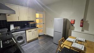 a kitchen with a refrigerator and a table in it at Spacious 2 Bedroom Flat in Coatbridge in Coatbridge