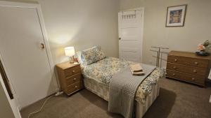 a bedroom with a bed and a dresser with a lamp at Spacious 2 Bedroom Flat in Coatbridge in Coatbridge