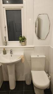 a bathroom with a toilet and a sink and a mirror at Spacious 2 Bedroom Flat in Coatbridge in Coatbridge