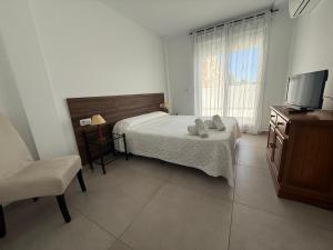a bedroom with a bed and a television and a chair at Living one Bed and Breakfast in Peniscola