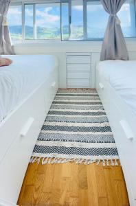 two beds in a room with a rug at Ilhéu à Vista in Água de Alto