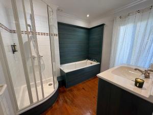 a bathroom with a tub and a shower and a sink at La parenthèse du port in Perros-Guirec