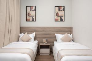 two beds in a hotel room with white walls at Liora Al Yasmin District in Riyadh +69 photos