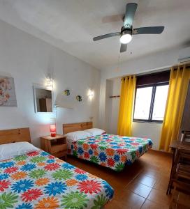 a bedroom with two beds and a ceiling fan at Residencia do Parque in Odeceixe