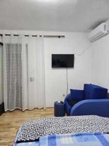 a living room with a blue couch and a tv at Apartman Ceca in Lepterija