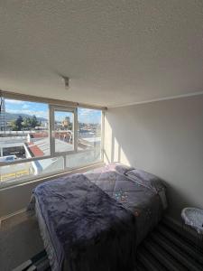 a bedroom with a bed and a large window at Departamento 610 in Temuco