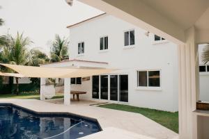 a white house with a swimming pool in front of it at Casa La Yola in Monterrico
