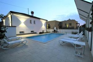 a patio with a pool and chairs and a house at House Casa Fabris with Pool in Umag