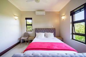 a bedroom with a large bed with a red blanket at The Pearl Ballito in Ballito