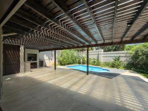 a patio with a wooden pergola and a swimming pool at The Pearl Ballito in Ballito