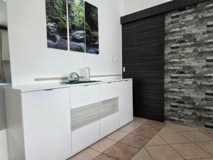 a kitchen with white cabinets and a brick wall at Nova Residence in Pula