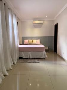 a bedroom with a bed with pink sheets and curtains at CASA AMPLA e MODERNA com Suíte in Porto Velho