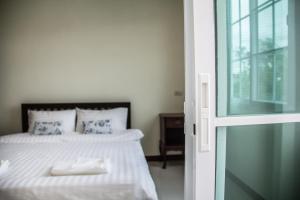 um quarto com uma cama com lençóis brancos e uma janela em Plern Pitch Residence em Pak Chong