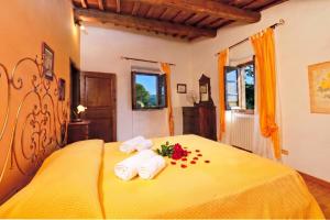 a bedroom with a yellow bed with towels and flowers at Casa Citille - Happy Rentals in Greve in Chianti