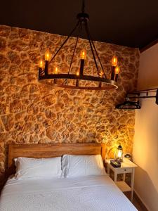 a bedroom with a stone wall with a bed and a chandelier at Utopía Alicante - Hotel Boutique para adultos in Alicante