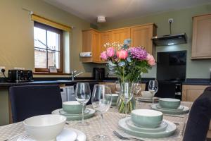 a dining table with a vase of flowers and wine glasses at 3 Breckan Brae in Orkney +23 photos
