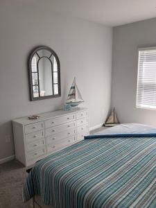 a bedroom with a bed and a dresser and a mirror at Sunset Beach townhome close to everything in Ocean Isle Beach +13 photos