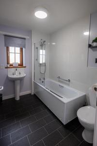 a bathroom with a tub and a toilet and a sink at 3 Breckan Brae in Orkney