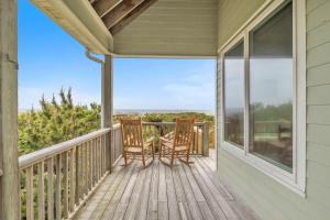a porch with two rocking chairs on it at Azohva by Oak Island Accommodations in Caswell Beach