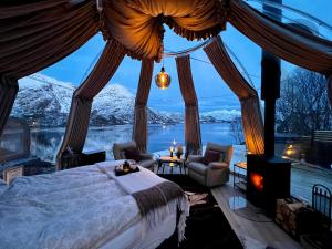 a bedroom with a bed and a view of snow covered mountains at Lofoten Glamping Dome in Myrland
