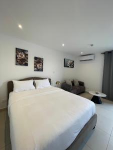a bedroom with a large white bed and a couch at Delali Residence at The Bantree 5 mins from Airport in Accra +6 photos