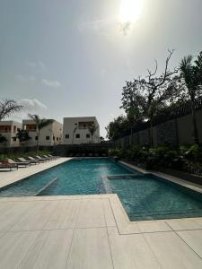 a swimming pool with chairs and trees and a building at Delali Residence at The Bantree 5 mins from Airport in Accra