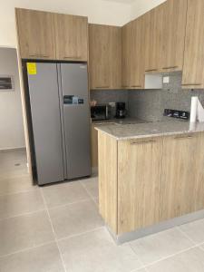 a kitchen with a refrigerator and wooden cabinets at Samana condo by the beach in Las Terrenas