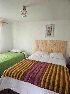 a bedroom with two beds with a colorful striped blanket at Real Casona Chacas in Chacas