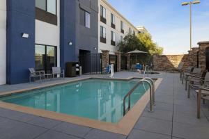 a swimming pool with chairs and a building at SpringHill Suites by Marriott Lancaster Palmdale in Lancaster
