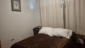 a small bedroom with a bed with a pillow at Cabaña con chimenea Paipa in Paipa