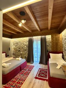 a bedroom with two beds and a stone wall at Golden Villa in Theth