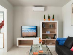 a living room with a flat screen tv on a white cabinet at Bungalow San Agustin Rocas Rojas in San Agustin