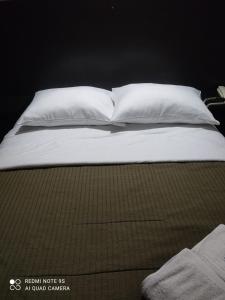 a bed with white sheets and pillows on it at Mihostal Bless in Tacna