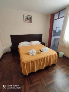 a bedroom with a bed with two slippers on it at Mihostal Bless in Tacna