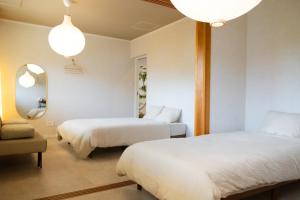 a bedroom with two beds and a mirror and a chair at YMA House in Nago