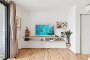 a living room with a tv on a white wall at Alamanda 114 Oceanview 2BR Steps from Orient Bay in Orient Bay