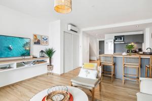 a living room with a large tv and a kitchen at Alamanda 114 Oceanview 2BR Steps from Orient Bay in Orient Bay +30 photos