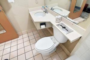 a bathroom with a toilet and a sink and a mirror at Airport Inn Memphis Near Graceland By Hotel O in Memphis +17 photos