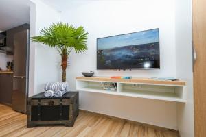 a living room with a tv on a wall at Studio 6 Alamanda Resort Orient Bay in Orient Bay