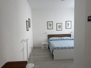 a white bedroom with a bed and pictures on the wall at A102 La Filanda by Larihome in Pianello Del Lario