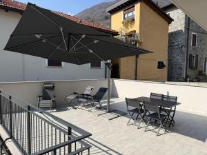 a patio with a table and chairs and an umbrella at A102 La Filanda by Larihome in Pianello Del Lario