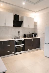 a kitchen with white cabinets and a stove top oven at Cutting Edge Guest House in Daranka