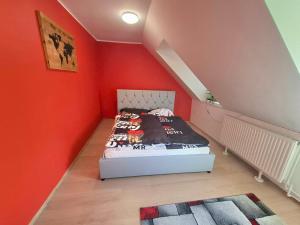 a bedroom with a bed in a red wall at KissApartman in Kőszeg